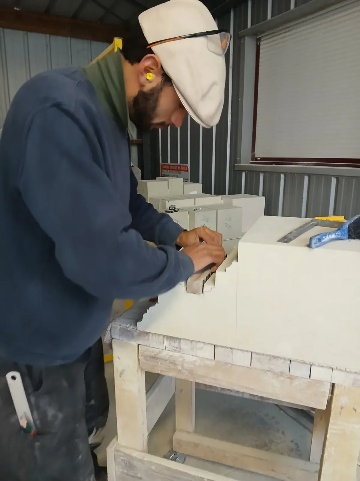 Compagnon de l'atelier Lapidis taillant la pierre