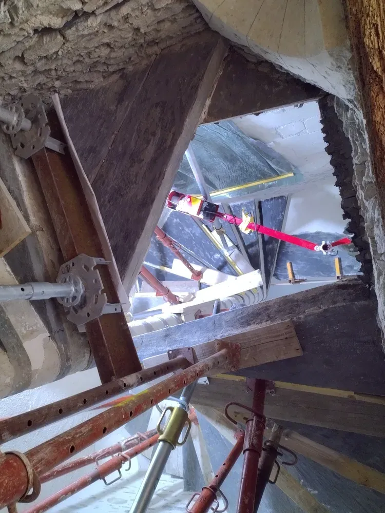 Marches de l'escalier à noyau en cours de pose, soutenues par des étais