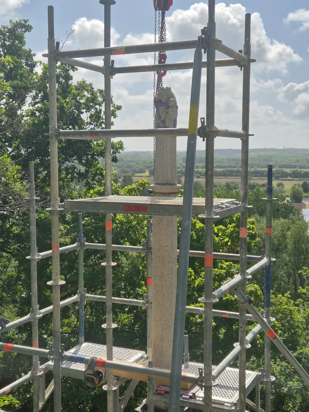 Levage à la grue de la statue sommitale au-dessus de l'échafaudage